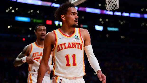 Trae Young and John Collins walk towards the bench.